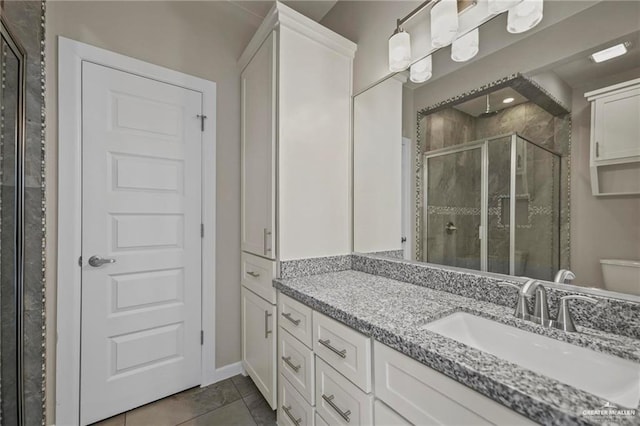 bathroom with tile patterned floors, a shower stall, toilet, vanity, and baseboards