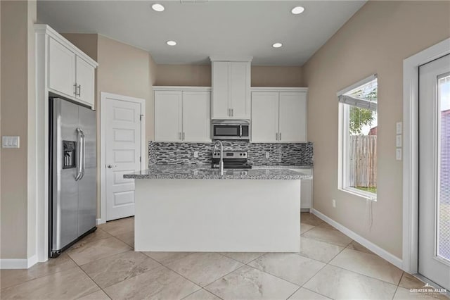 kitchen with white cabinetry, stainless steel appliances, a center island with sink, and backsplash