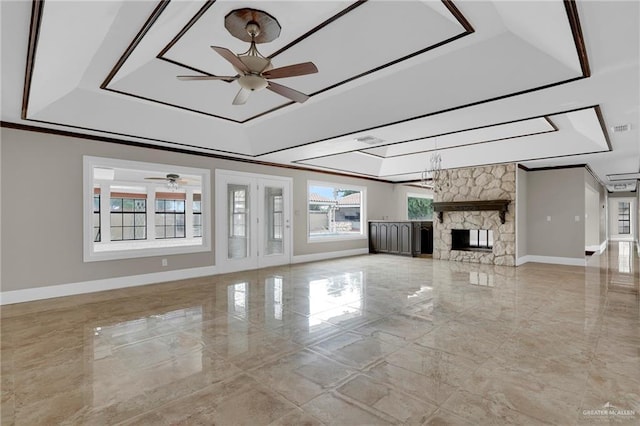 unfurnished living room with baseboards, a ceiling fan, a raised ceiling, and marble finish floor