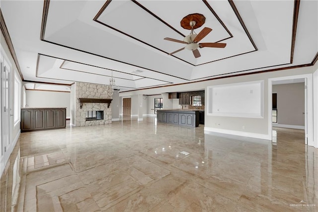 unfurnished living room with ceiling fan, a fireplace, marble finish floor, baseboards, and a tray ceiling