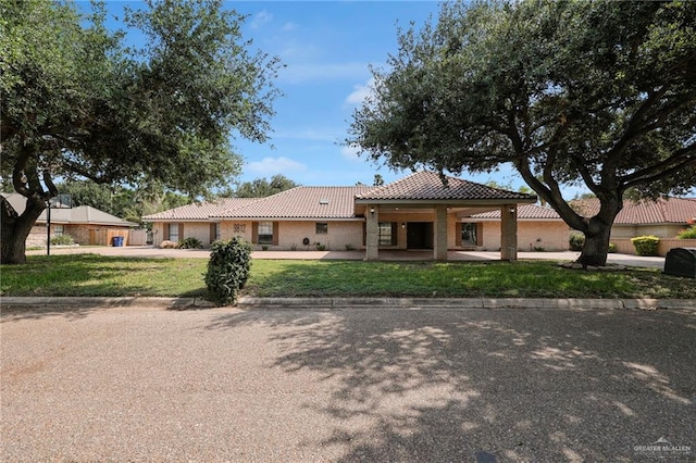 view of front of home featuring a front lawn, stucco siding, a tiled roof, and driveway