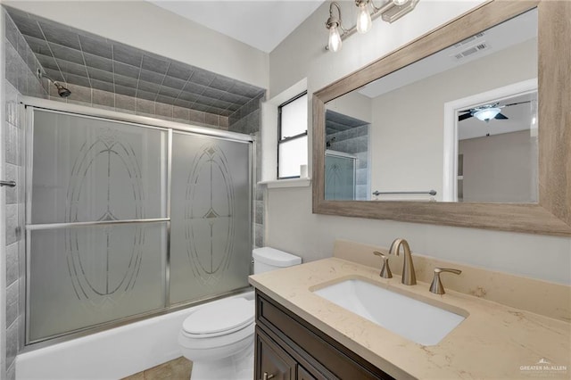 bathroom with visible vents, combined bath / shower with glass door, toilet, and vanity