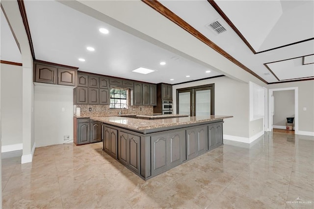 kitchen featuring baseboards, recessed lighting, dark brown cabinetry, and a spacious island