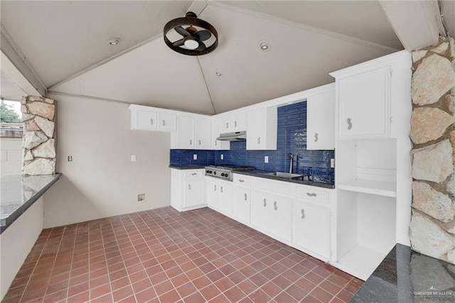kitchen with a sink, dark countertops, stainless steel gas cooktop, and vaulted ceiling