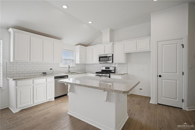 8306 N 34th Ln, Mcallen, TX 78504 - kitchen featuring appliances with stainless steel finishes, wood finished floors, white cabinets, a kitchen island, and vaulted ceiling