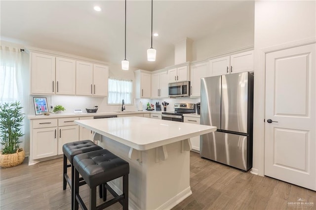 kitchen with white cabinetry, a center island, a kitchen breakfast bar, pendant lighting, and stainless steel appliances