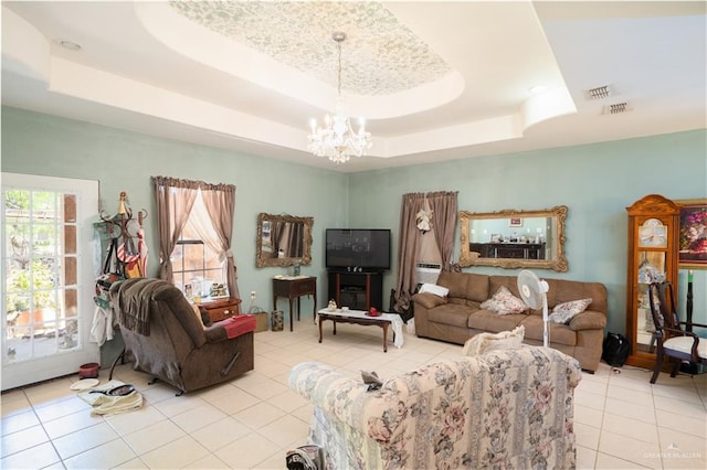 living room featuring a tray ceiling, light tile patterned floors, and an inviting chandelier