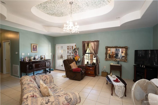 living room featuring light tile patterned flooring, a raised ceiling, and an inviting chandelier