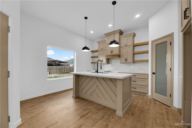 kitchen with decorative backsplash, light hardwood / wood-style flooring, an island with sink, and hanging light fixtures