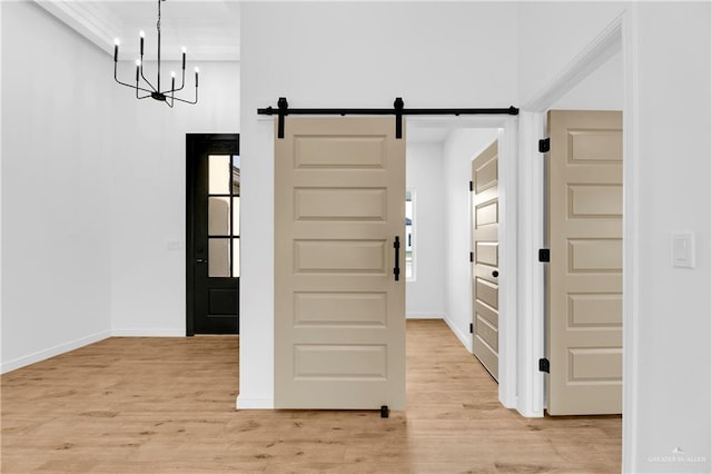 interior space with a barn door, light hardwood / wood-style floors, and an inviting chandelier