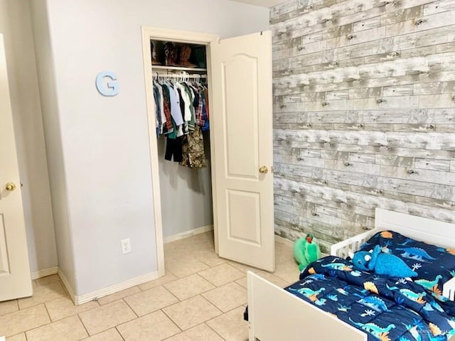 bedroom with light tile patterned floors, a closet, and wood walls