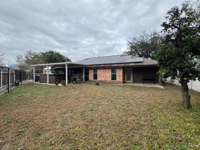 back of house with solar panels and a yard