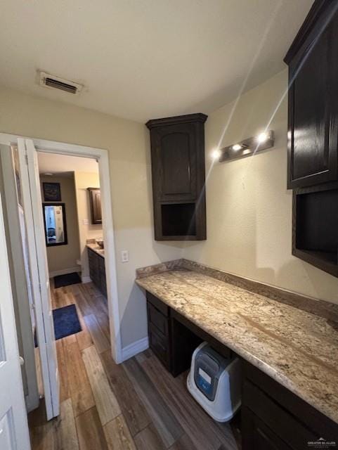 kitchen with light stone countertops, built in desk, and dark hardwood / wood-style floors