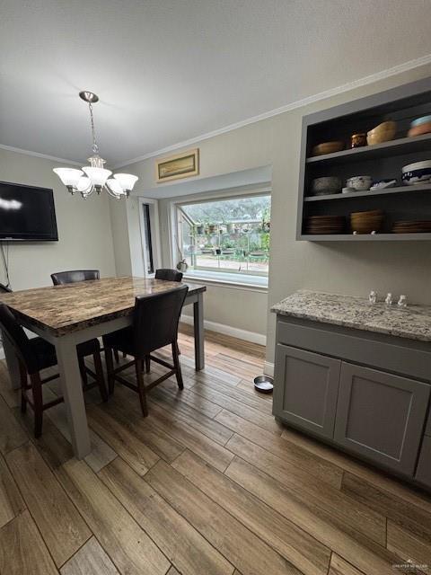 dining area featuring built in shelves, light wood-type flooring, ornamental molding, and an inviting chandelier