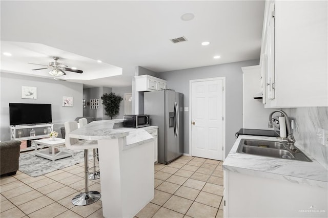 kitchen featuring open floor plan, a breakfast bar, appliances with stainless steel finishes, white cabinetry, and recessed lighting