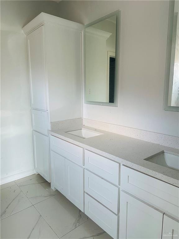 full bath featuring marble finish floor, a sink, and double vanity