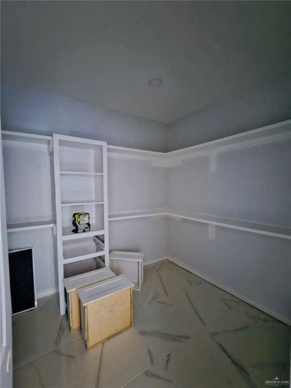 walk in closet featuring marble finish floor