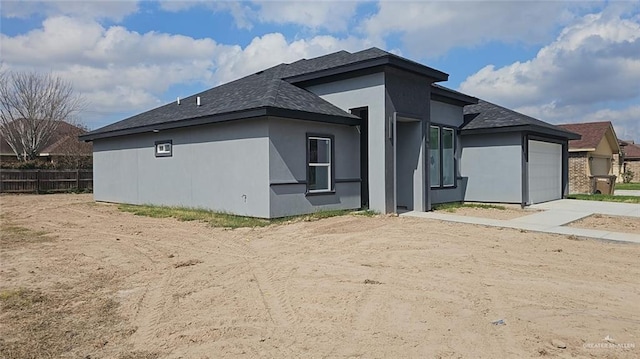 back of property featuring an attached garage, driveway, fence, and stucco siding