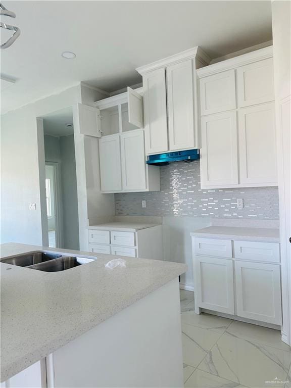 kitchen featuring light stone counters, marble finish floor, white cabinets, and tasteful backsplash