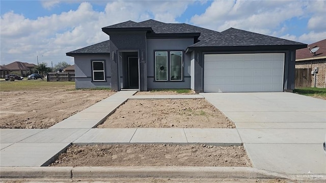 view of front facade with a garage, concrete driveway, a shingled roof, and stucco siding