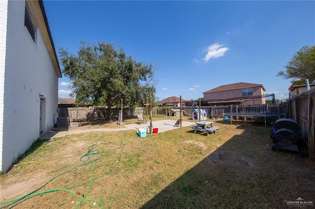 view of yard with a trampoline and central air condition unit