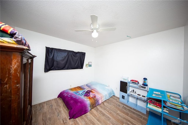 bedroom with hardwood / wood-style flooring, ceiling fan, and a textured ceiling