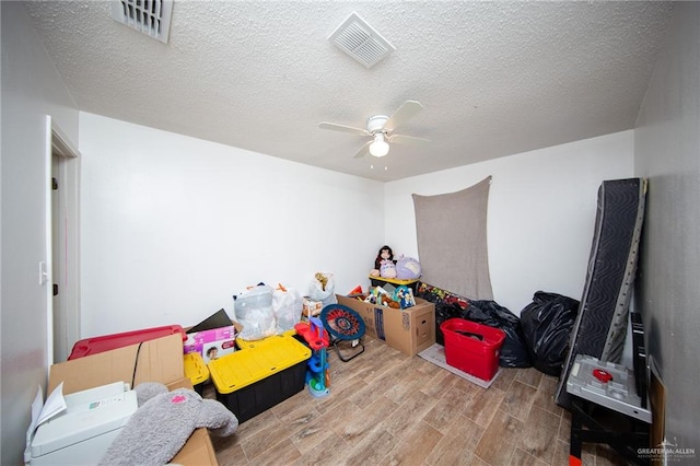 rec room with hardwood / wood-style floors, a textured ceiling, and ceiling fan