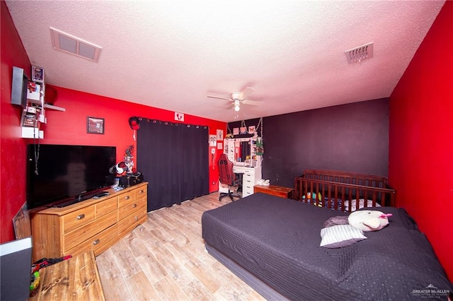 bedroom with a textured ceiling, light wood-type flooring, and ceiling fan