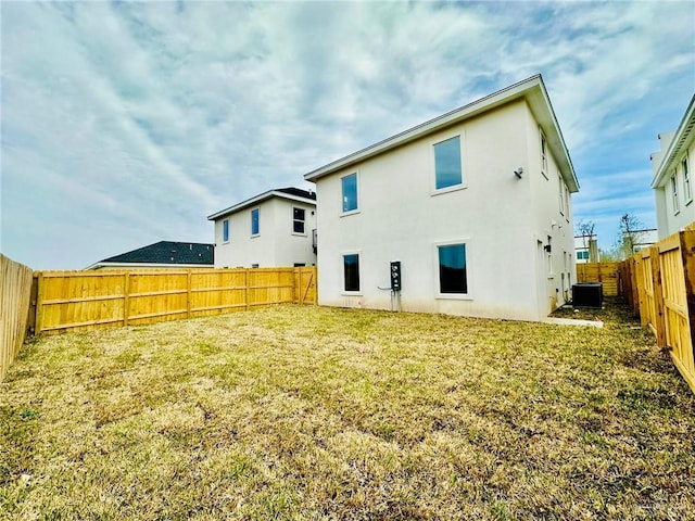 rear view of property featuring central AC unit and a yard