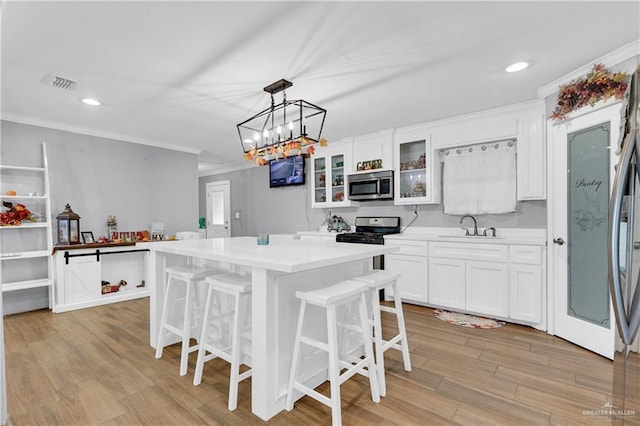 kitchen featuring a center island, light hardwood / wood-style floors, pendant lighting, white cabinets, and appliances with stainless steel finishes