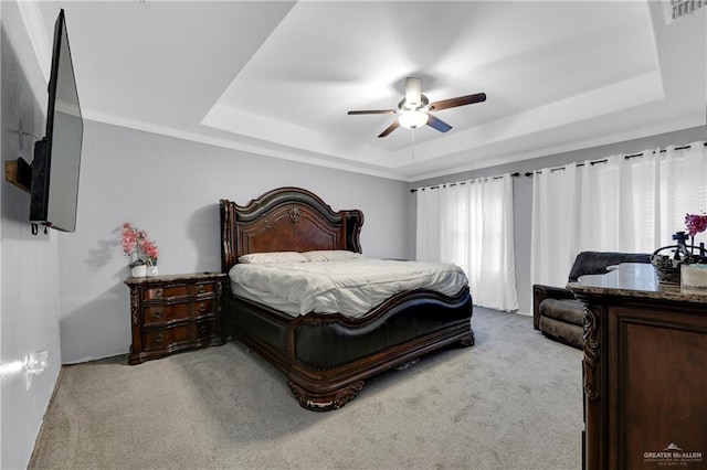 carpeted bedroom featuring a tray ceiling, ceiling fan, and crown molding