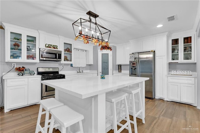 kitchen with a breakfast bar, appliances with stainless steel finishes, light hardwood / wood-style flooring, and white cabinetry