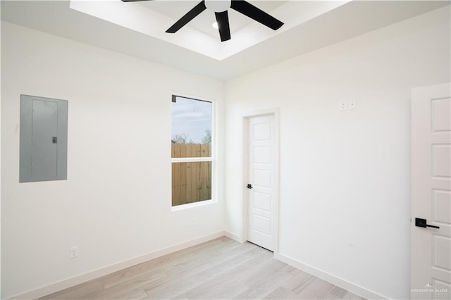 unfurnished room featuring a tray ceiling, light hardwood / wood-style flooring, electric panel, and ceiling fan