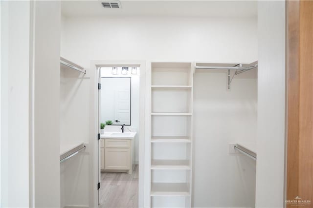 walk in closet with light hardwood / wood-style floors and sink