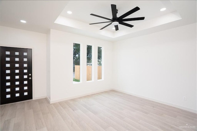 unfurnished room featuring light hardwood / wood-style flooring, a raised ceiling, and ceiling fan