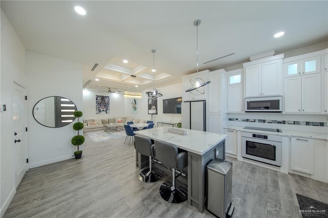 kitchen with tasteful backsplash, black electric stovetop, white oven, coffered ceiling, and white cabinetry