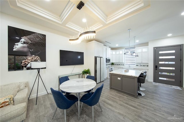 dining room with light wood-style flooring, coffered ceiling, crown molding, and baseboards