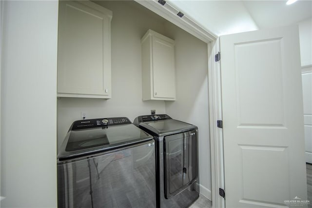 clothes washing area with separate washer and dryer and cabinet space