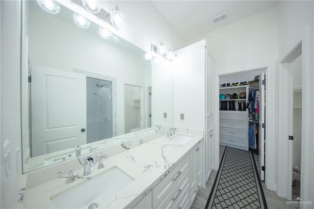 bathroom with a walk in closet, a shower stall, visible vents, and a sink