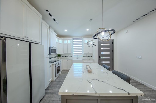 kitchen featuring a kitchen island, a sink, white cabinets, light wood-style floors, and appliances with stainless steel finishes