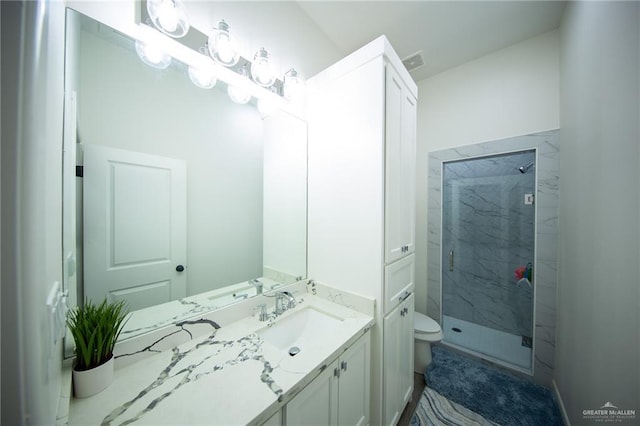 full bath featuring a marble finish shower, visible vents, toilet, and vanity