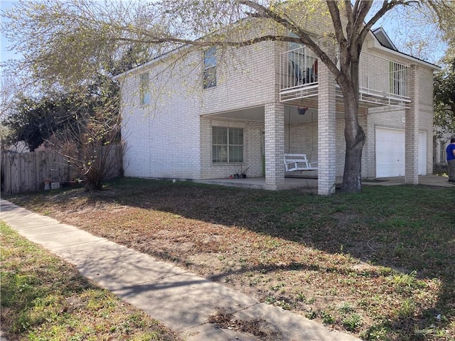 view of front of home featuring a patio, a garage, fence, and brick siding