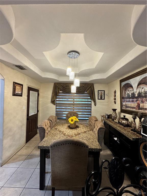 704 S 17th St, Hidalgo, TX 78557 - dining space featuring a raised ceiling, light tile patterned flooring, and a chandelier