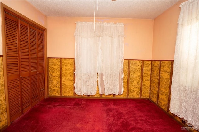 empty room with a textured ceiling and dark carpet