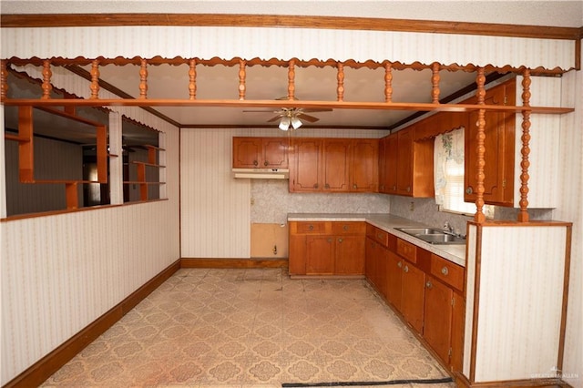 501 N Park Ave, Pharr, TX 78577 - kitchen with wallpapered walls, ceiling fan, light countertops, brown cabinets, and under cabinet range hood