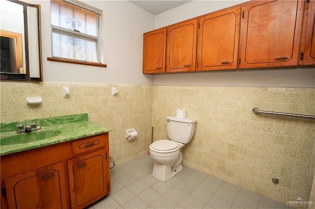 bathroom featuring tile patterned floors, vanity, toilet, and tile walls