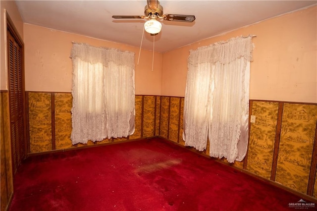 empty room featuring dark colored carpet and ceiling fan