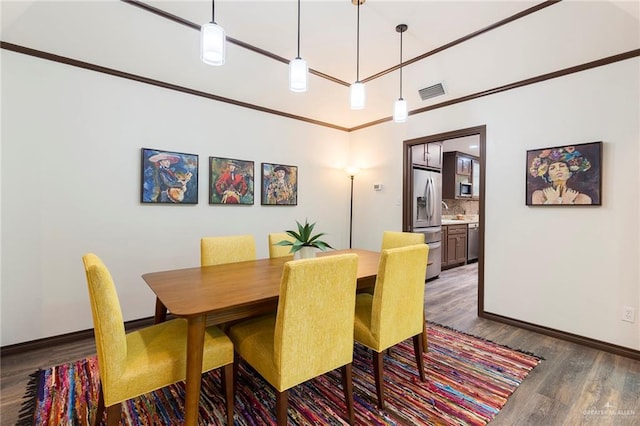 dining area featuring dark hardwood / wood-style floors and crown molding