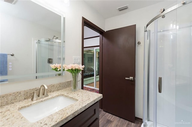 bathroom featuring wood-type flooring, vanity, and an enclosed shower