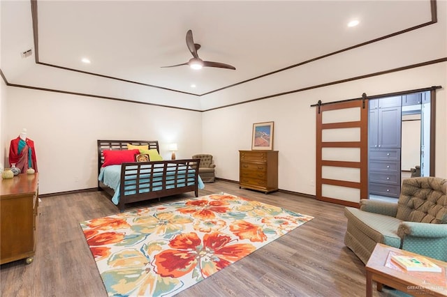 bedroom featuring a barn door, ceiling fan, and hardwood / wood-style flooring